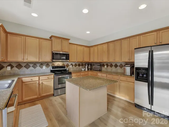 a kitchen with stainless steel appliances granite countertop a stove a sink and a microwave