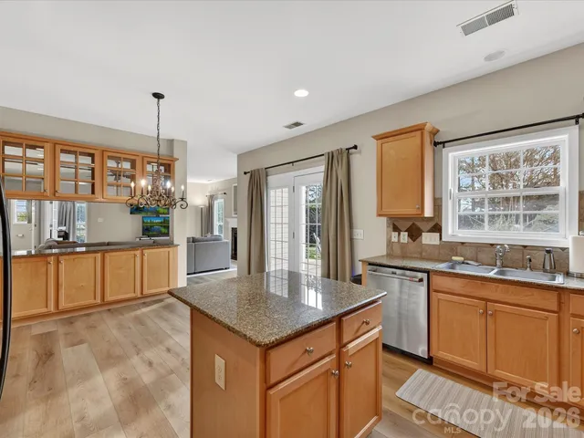 a kitchen with stainless steel appliances granite countertop a stove a sink and a refrigerator with wooden floor