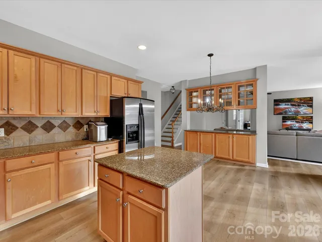 a kitchen with stainless steel appliances granite countertop a refrigerator cabinets and wooden floor