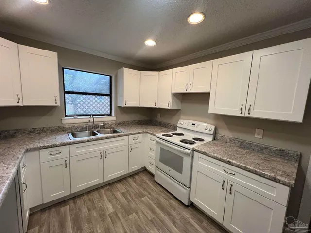 a kitchen with granite countertop white cabinets and white appliances