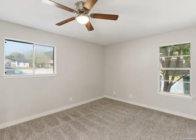 an empty room with a window and a fan