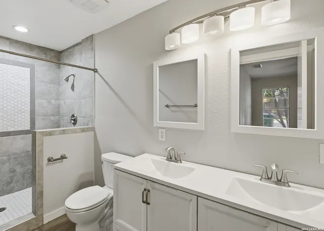 a bathroom with a sink toilet vanity and shower
