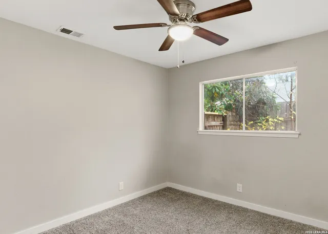 an empty room with a window and a fan