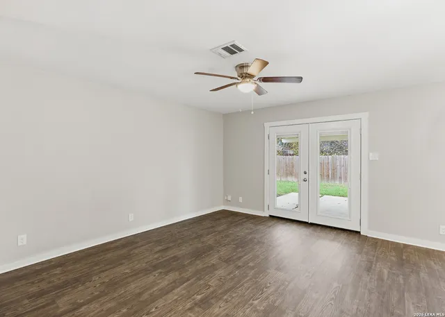 a view of an empty room with a window and wooden floor