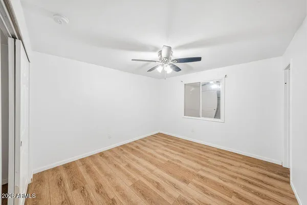 a view of a big room with wooden floor and chandelier fan