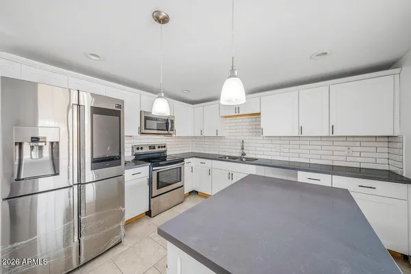 a kitchen with granite countertop a sink stainless steel appliances and white cabinets