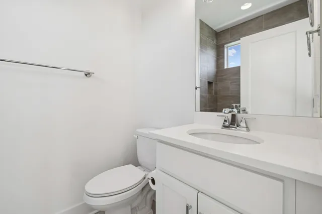 a bathroom with a toilet sink vanity and mirror