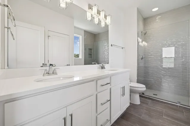 a bathroom with a double vanity sink toilet and a mirror