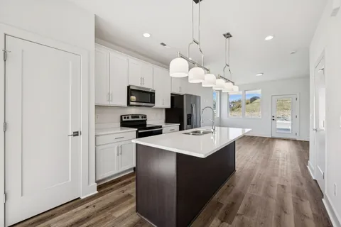 a large kitchen with cabinets a sink dishwasher a stove and a refrigerator with wooden floor