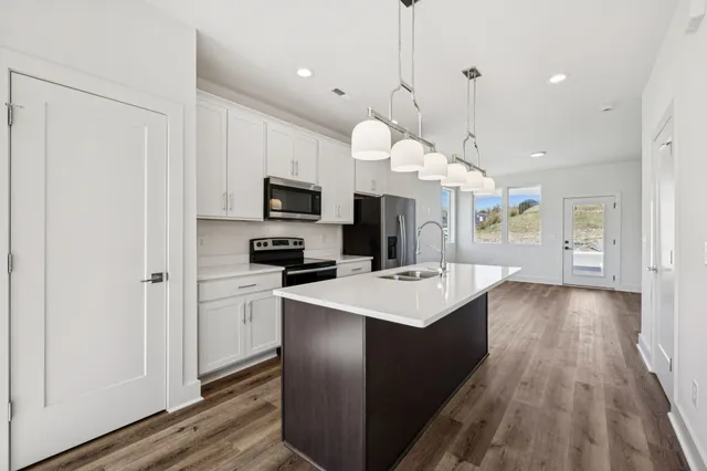 a large kitchen with cabinets a sink dishwasher a stove and a refrigerator with wooden floor