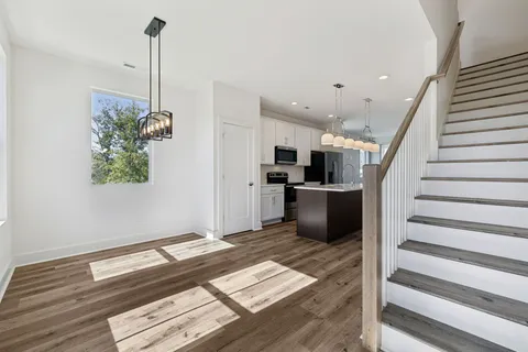 a kitchen with stainless steel appliances kitchen island granite countertop a refrigerator a stove and a wooden floor