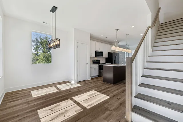 a kitchen with stainless steel appliances kitchen island granite countertop a refrigerator a stove and a wooden floor