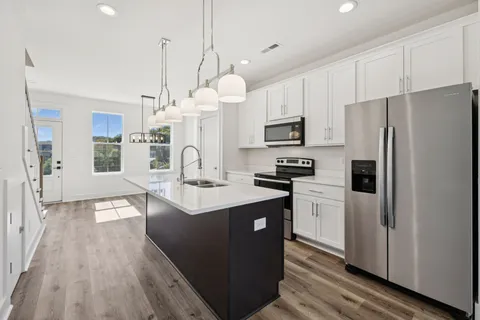 a kitchen with stainless steel appliances a refrigerator a stove a sink dishwasher and a refrigerator with wooden floor