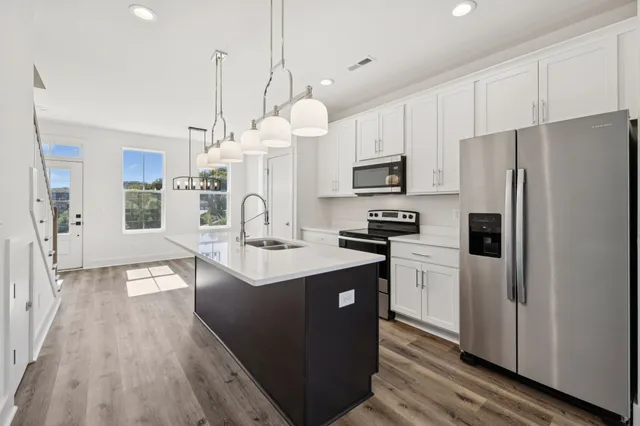 a kitchen with stainless steel appliances a refrigerator a stove a sink dishwasher and a refrigerator with wooden floor