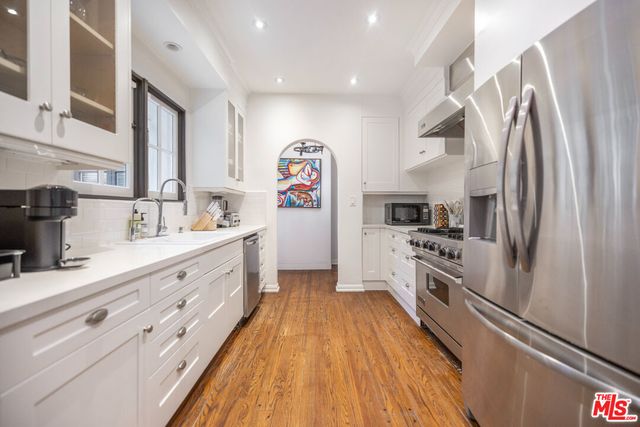 a kitchen with stainless steel appliances granite countertop a lot of counter space and wooden floors
