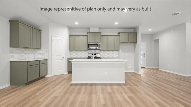 a large white kitchen with kitchen island a sink stainless steel appliances and cabinets