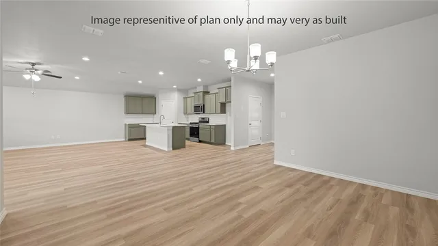 an empty room with wooden floor and kitchen view