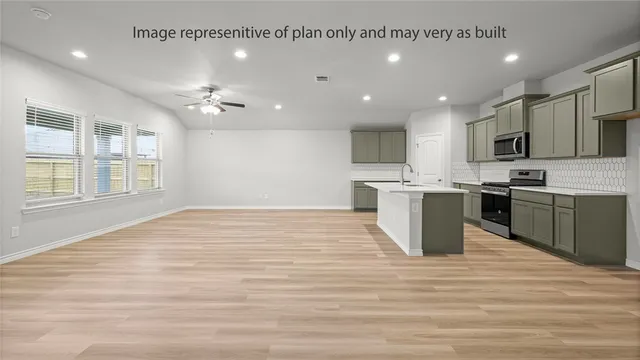a view of kitchen with stainless steel appliances granite countertop a stove top oven a sink dishwasher and white cabinets with wooden floor