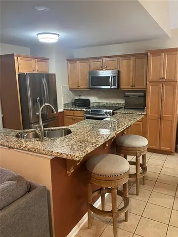 a kitchen with stainless steel appliances granite countertop a stove a sink a microwave a refrigerator and chairs