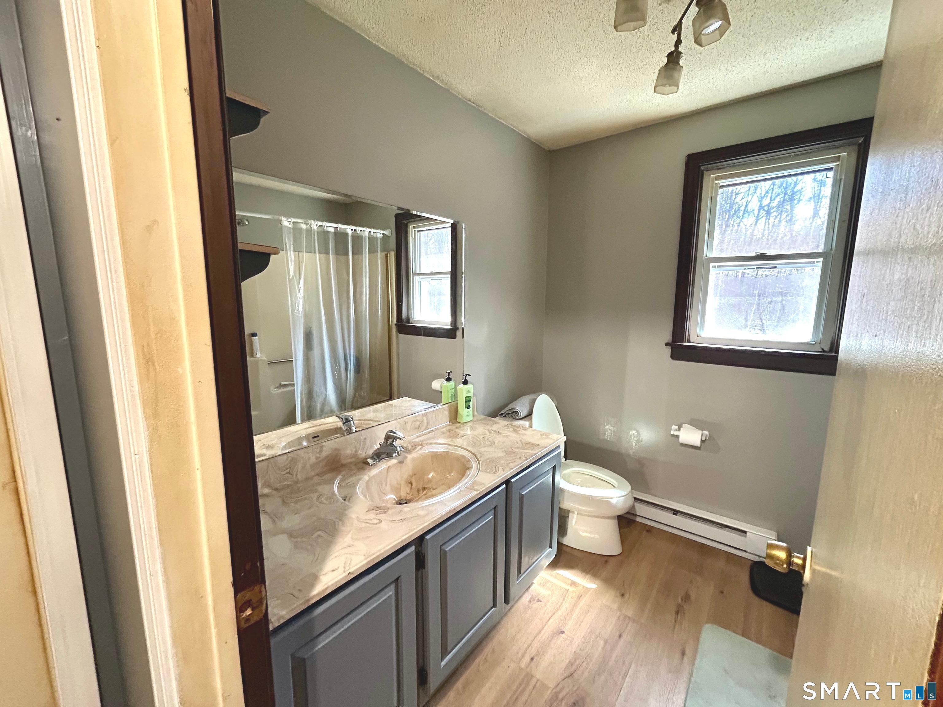 222 Parish Hill Road Scotland, CT 06264 - Photo 11 of 14 a bathroom with a granite countertop sink a large mirror a toilet and a window