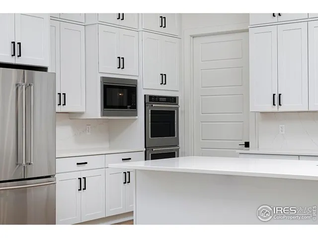 a kitchen with white cabinets and black appliances