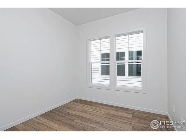 a view of an empty room with wooden floor and window