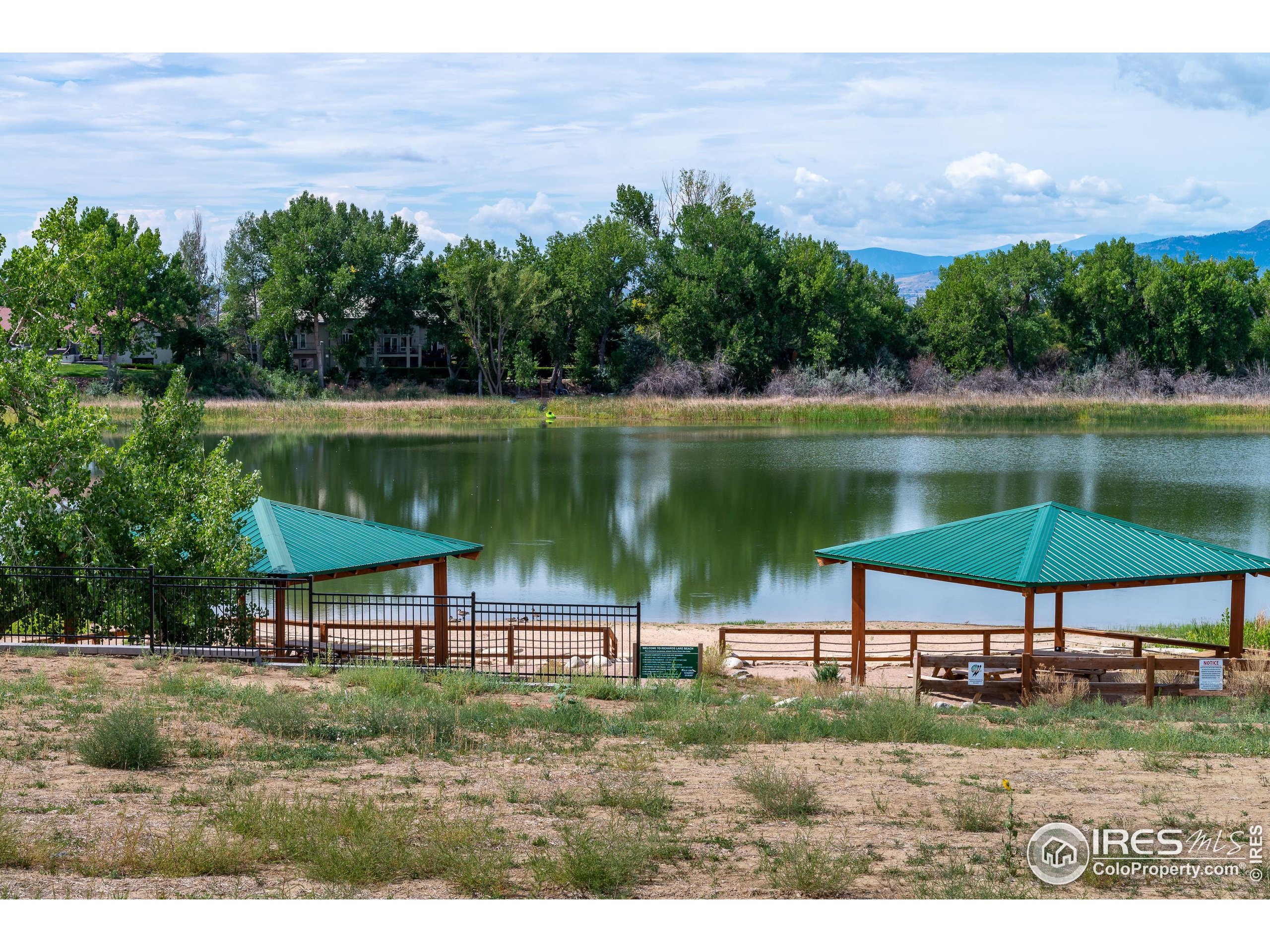 1738 Morningstar Way Fort Collins, CO 80524 - Photo 45 of 49 a view of a lake with a table and chairs under an umbrella