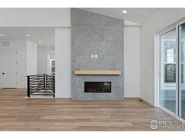 a view of an empty room with wooden floor and a fireplace