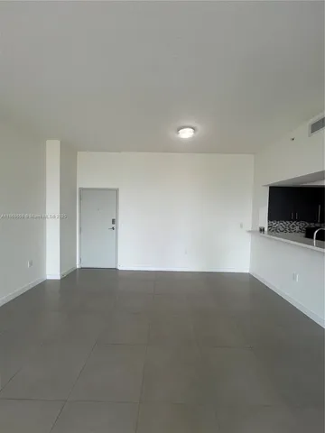 a view of an empty room and a kitchen