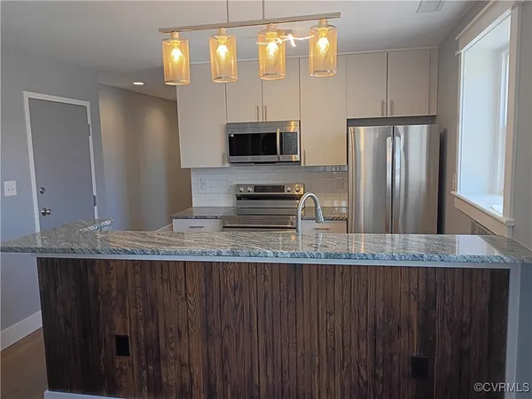 a kitchen with granite countertop a refrigerator a stove a sink and dishwasher