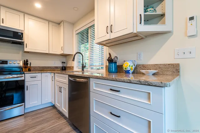 a kitchen with stainless steel appliances granite countertop a stove refrigerator a dining table and chairs with wooden floor