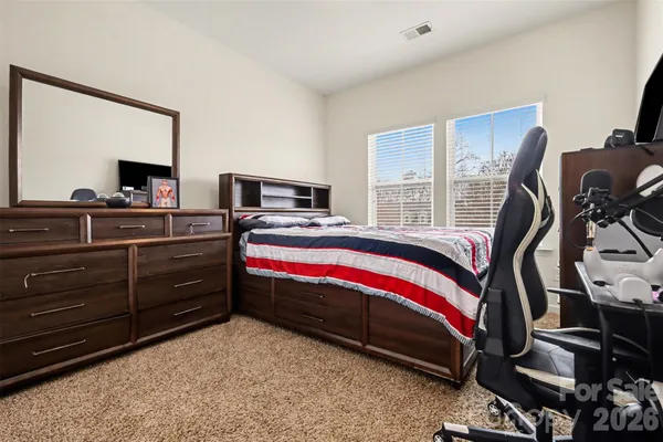 a bedroom with a bed and a flat tv screen on dresser