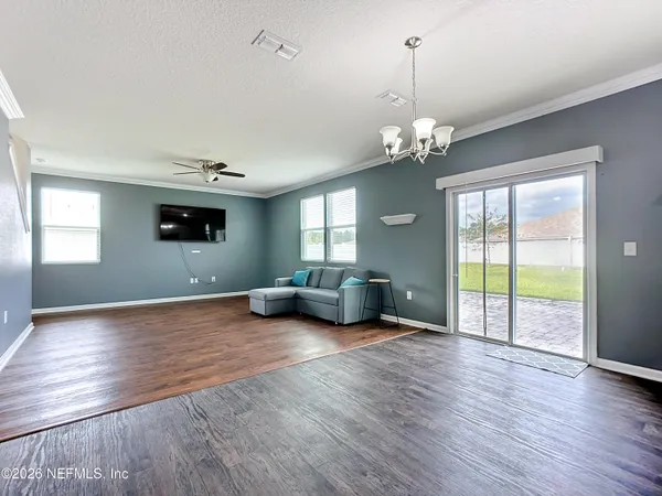 a view of an empty room with window and wooden floor