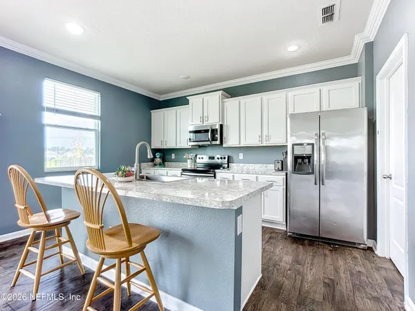 a kitchen with stainless steel appliances granite countertop a stove a sink a refrigerator with a dining table and chairs