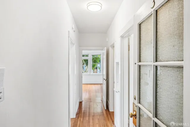 a view of a hallway with wooden floor and door