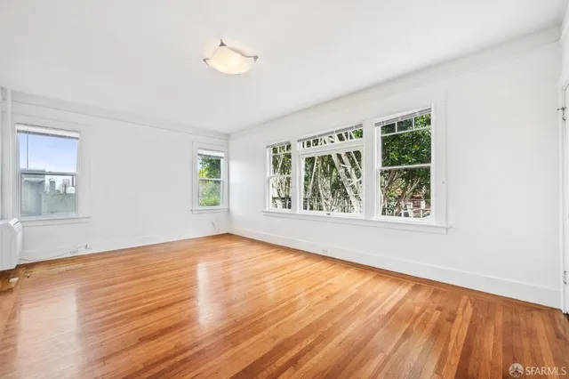 a view of an empty room with wooden floor and a window