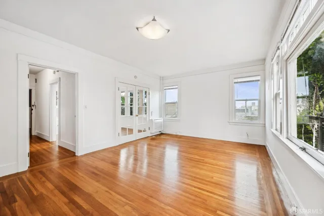 a view of empty room with wooden floor and fan