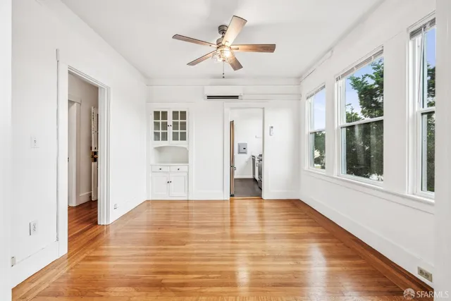 a view of an empty room with a window and kitchen view