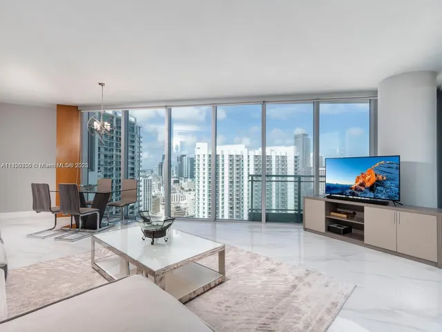 a living room with furniture a flat screen tv and floor to ceiling window