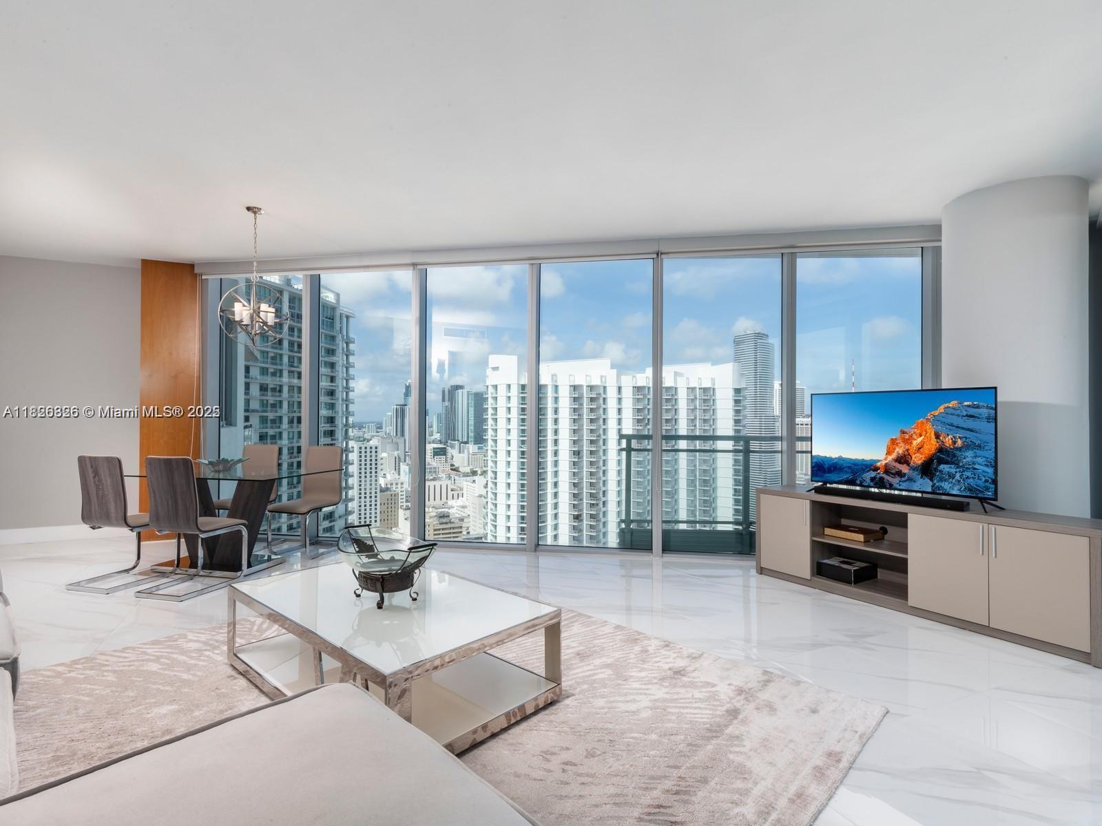 92 Southwest 3rd Street, Unit 3901 Miami, FL 33130 - Photo 2 of 10 a living room with furniture a flat screen tv and floor to ceiling window