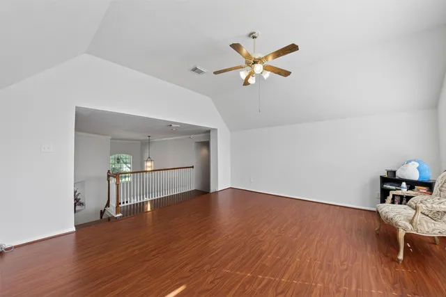 a view of empty room with wooden floor and fan