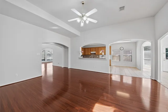 a view of an empty room with wooden floor and a window