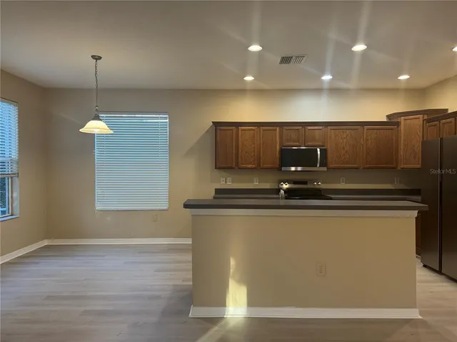 a view of an empty room with window and chandelier fan