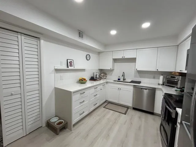 a kitchen with a refrigerator stove and white cabinets