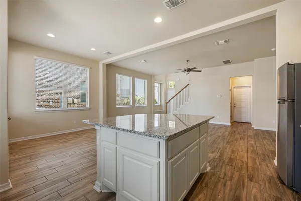 a kitchen with granite countertop a stove a sink and a refrigerator