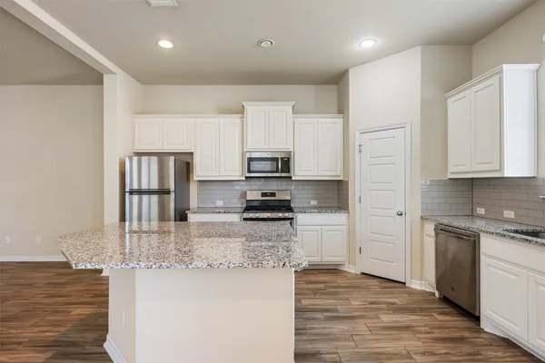 a kitchen with stainless steel appliances granite countertop a refrigerator a stove and a sink