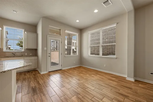 an empty room with wooden floor and windows