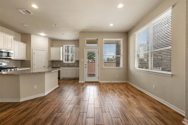 a large kitchen with cabinets wooden floor and stainless steel appliances