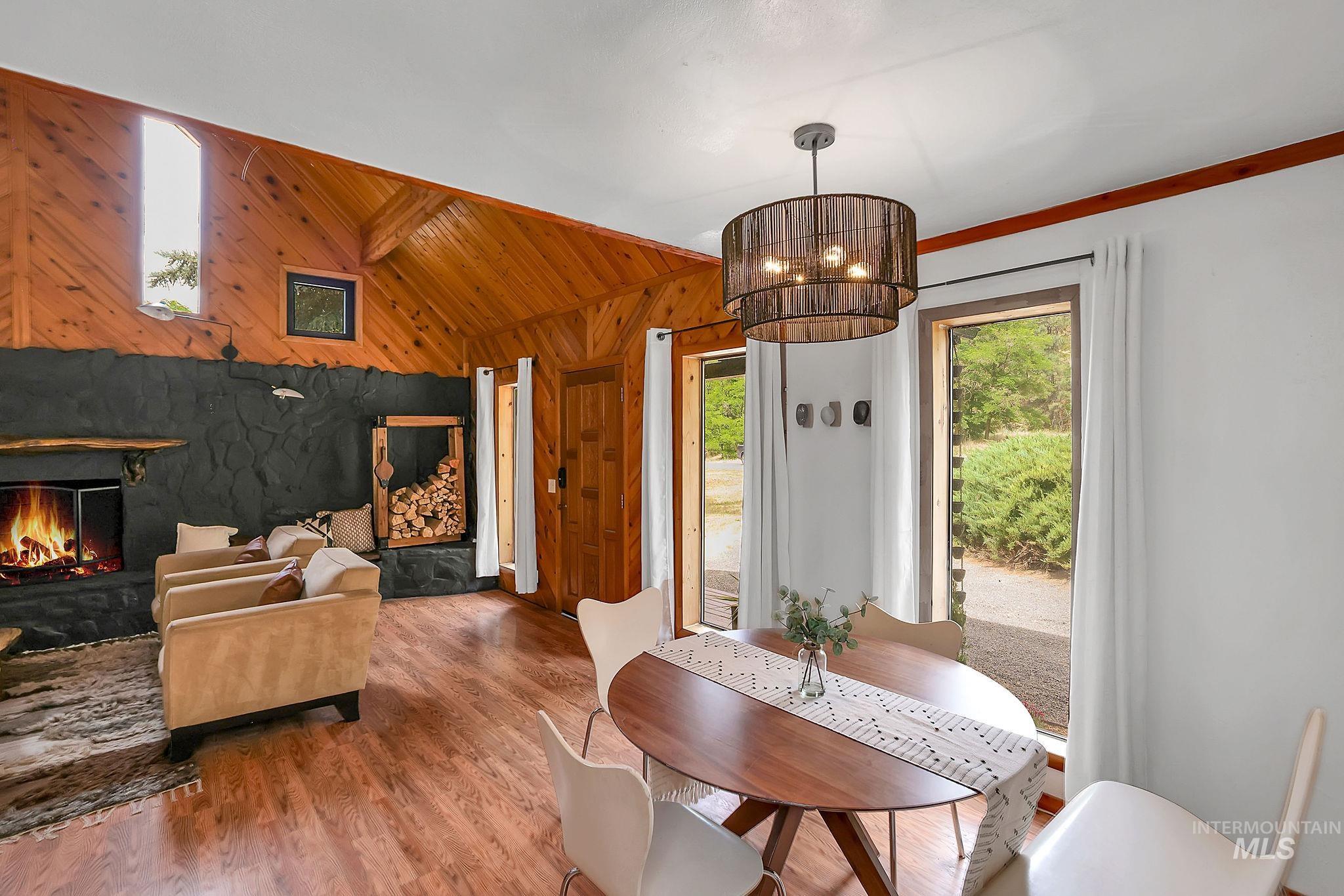 5713 Pines Road New Meadows, ID 83654 - Photo 11 of 45 Dining room featuring wooden walls, vaulted ceiling with beams, wood finished floors, and a warm lit fireplace