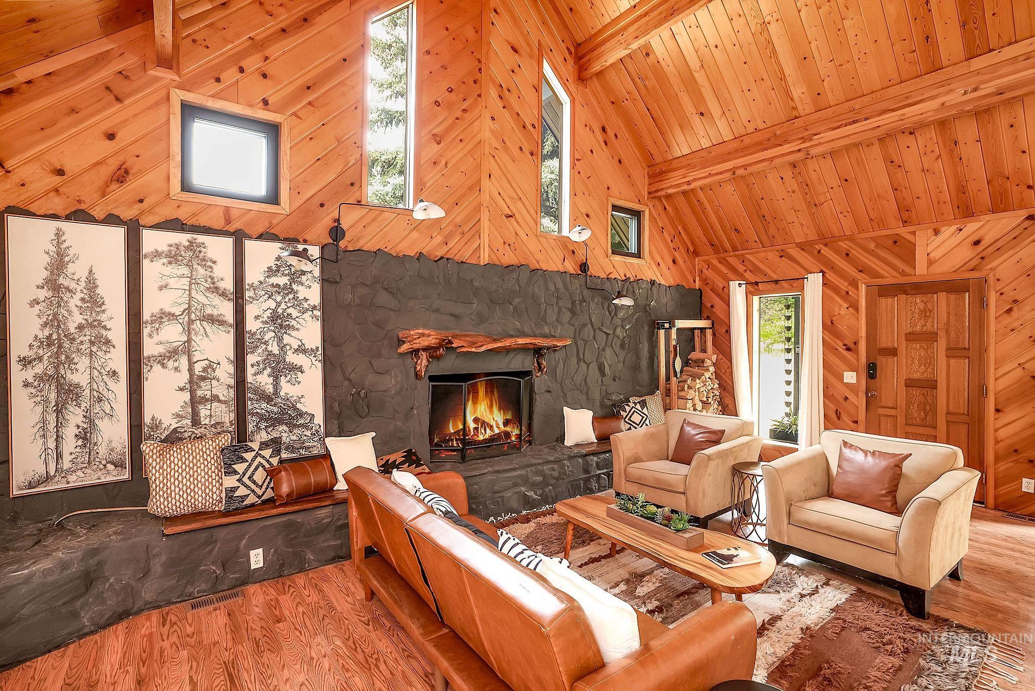 5713 Pines Road New Meadows, ID 83654 - Photo 7 of 45 Living area featuring a stone fireplace, wood finished floors, wood walls, and vaulted ceiling